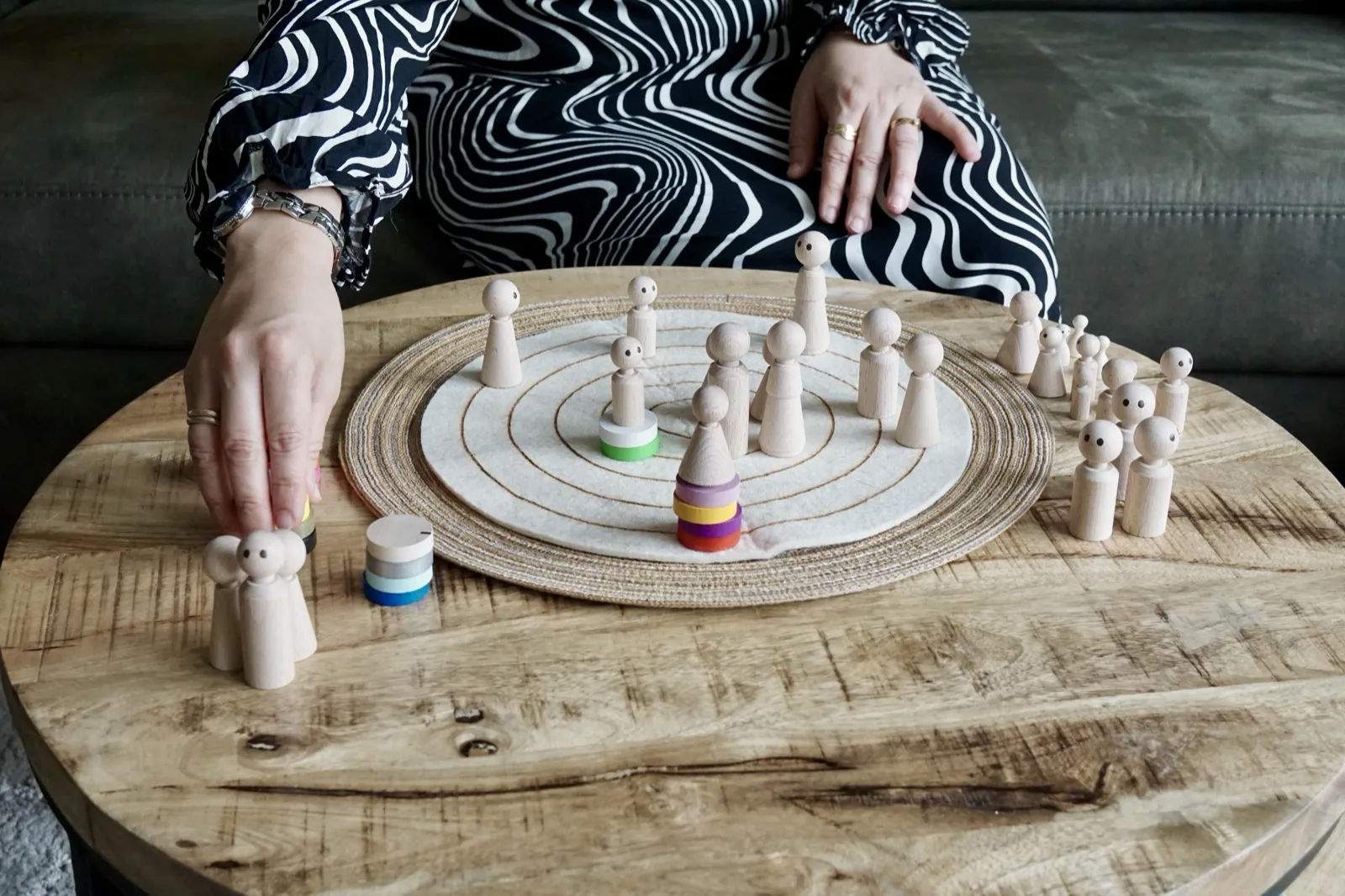 Handen en houten poppetjes tijdens een systemische opstelling